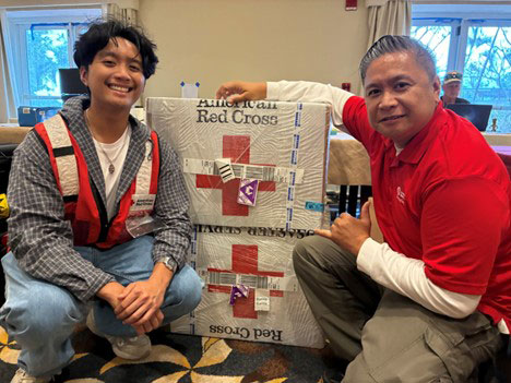 Nathan Paz and his father Ellery pose for picture next to red cross packages.
