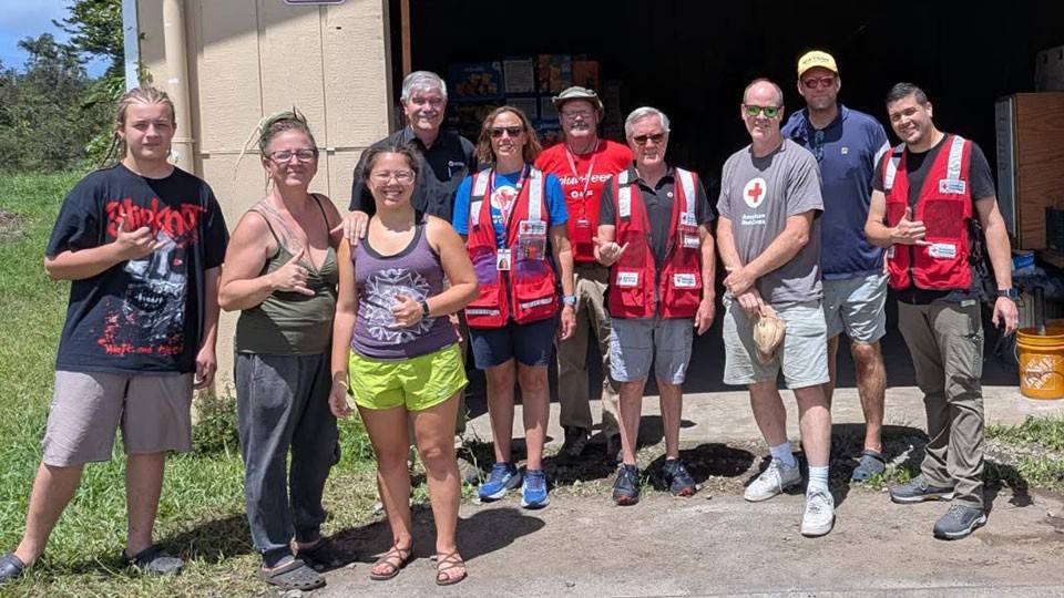 a group of Red Cross volunteers in front of a fire station.
