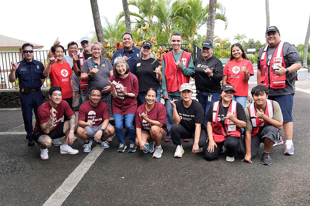 Group pic of Red Cross volunteers and firefighters all giving the shaka sign.