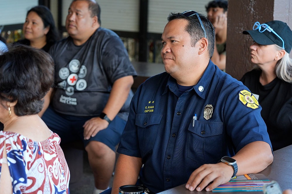 Local fire fighter and Red Cross volunteers sitting and listening in a room.