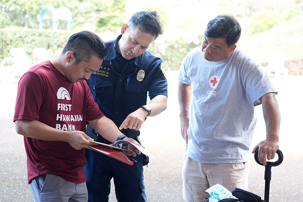 Local fire fighter and Red Cross volunteers looking at a clipboard.