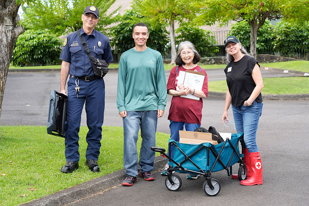 Local fire fighter and Red Cross volunteers standing next to a cart with supplies.