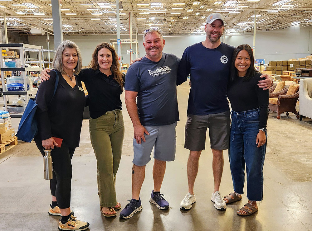 group pic of five people in a warehouse with a couple of them wearing ToolBank shirts.