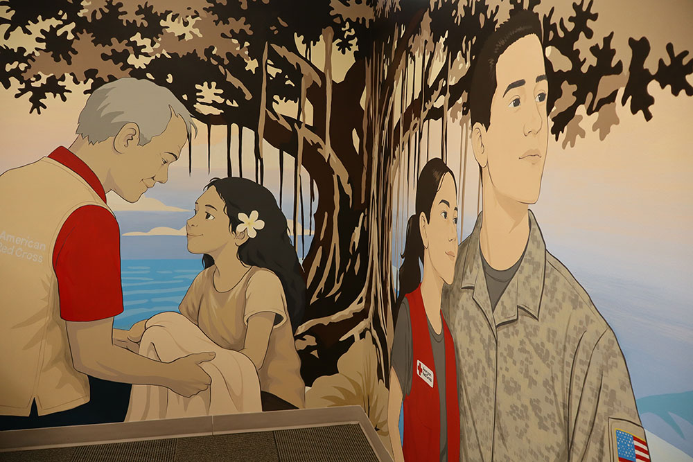 Mural painting on the inside wall of a Red Cross building of a Red Cross volunteer helping another person and a Red Cross volunteer with a soldier in camo.