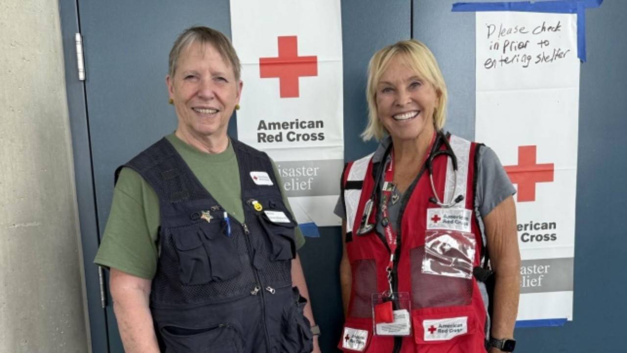 two red crossers standing in front of red cross signgage