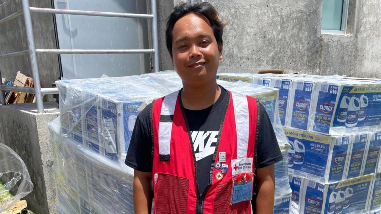 volunteer in red cross disaster vest standing in front of supplies