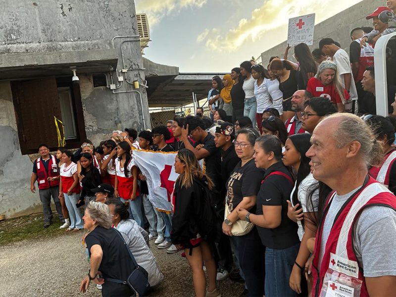 large group of people holding up red cross flag in saipan