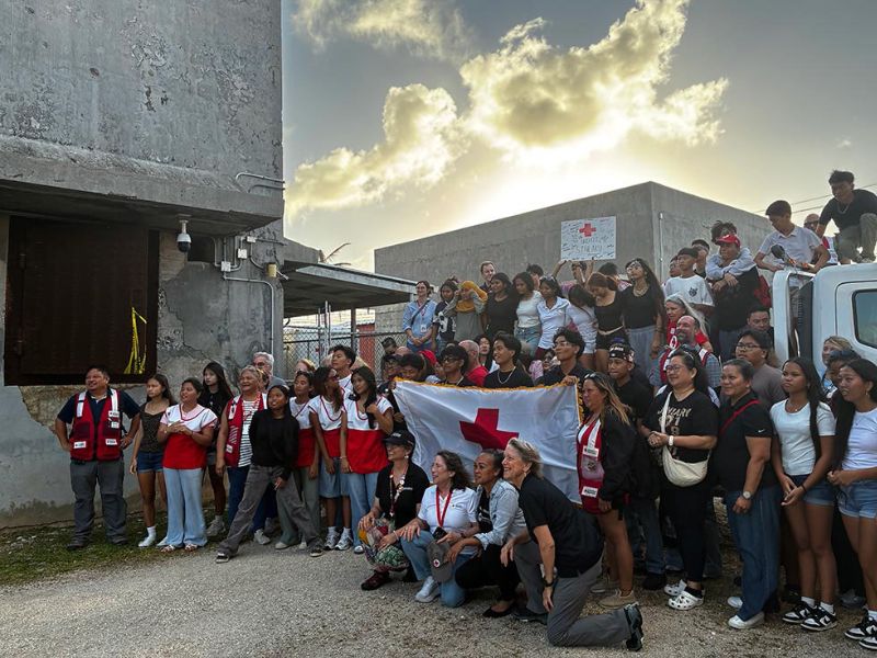 large group of people holding up red cross flag in saipan