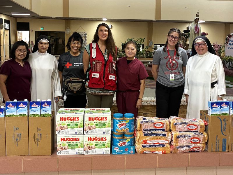 group of people smiling with boxes of food supplies