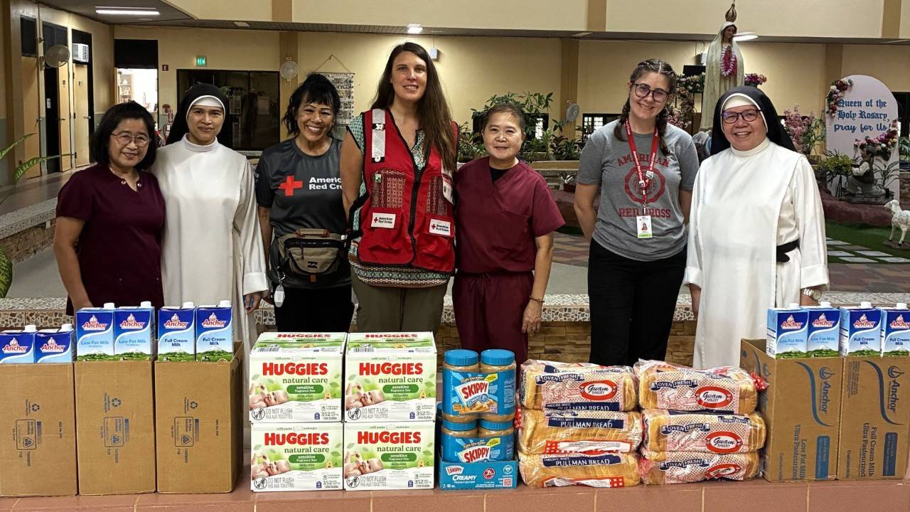 red crossers and church members gathered around packaged food supplies