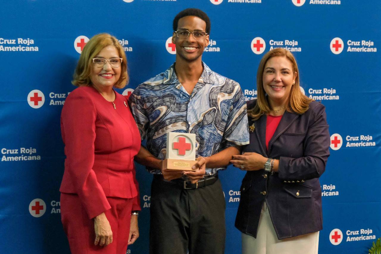 Edward Valentín galardonado como Joven Voluntario del Año de la 105 Asamblea Anual de la Cruz Roja Americana Capítulo de Puerto Rico. Le entregan el reconocimiento la Lcda. Janet Díaz Salicrup, presidenta de la Junta de Directores y Lee Vanessa Feliciano, ejecutiva regional de la Cruz Roja Americana Capítulo de Puerto Rico. 