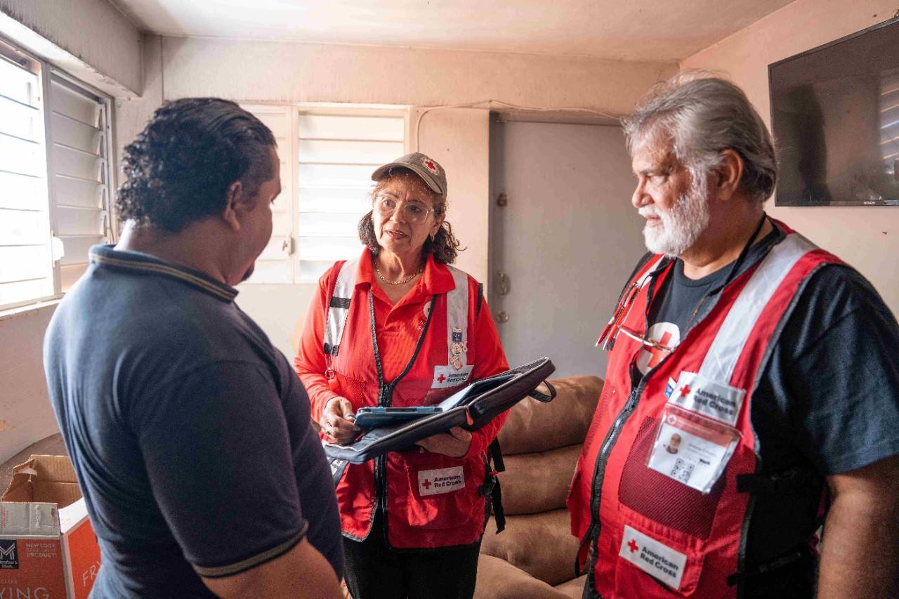 Carmen Sánchez, en el centro, acompañada de compañero voluntario Orlando Pizarro junto a un señor afectado por el fuego en su hogar. 