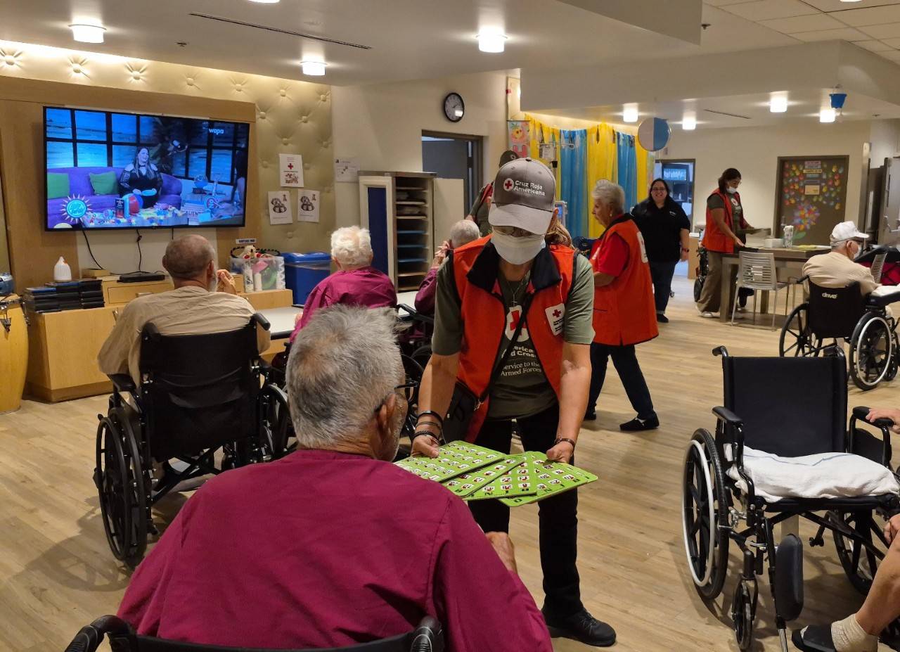 Voluntaria comparte con veterano durante actividad recreativa en el Hospital de Veteranos.