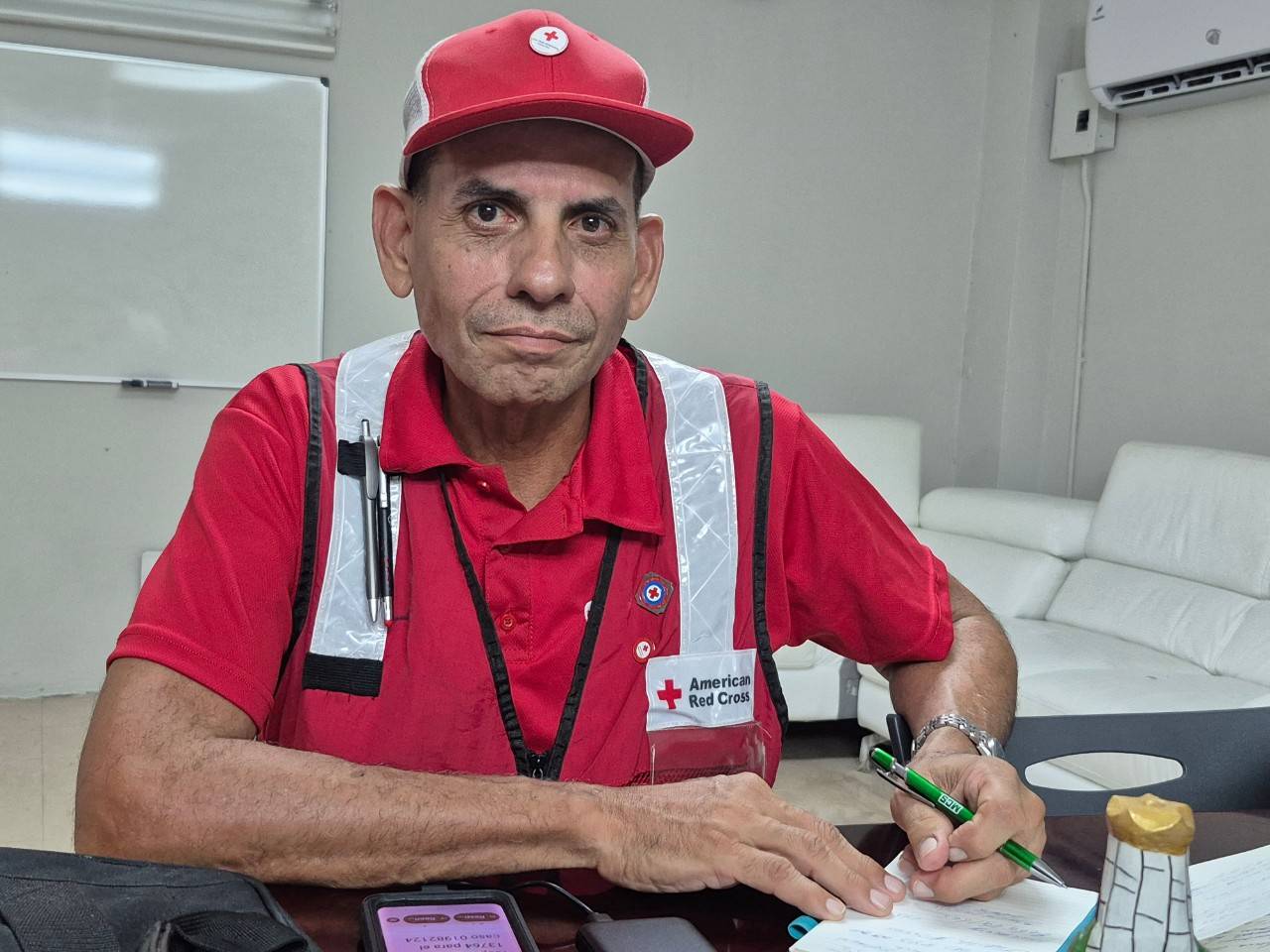 Pastor Medina mira a la cámara sentado en una mesa con papeles y un bolígrafo.