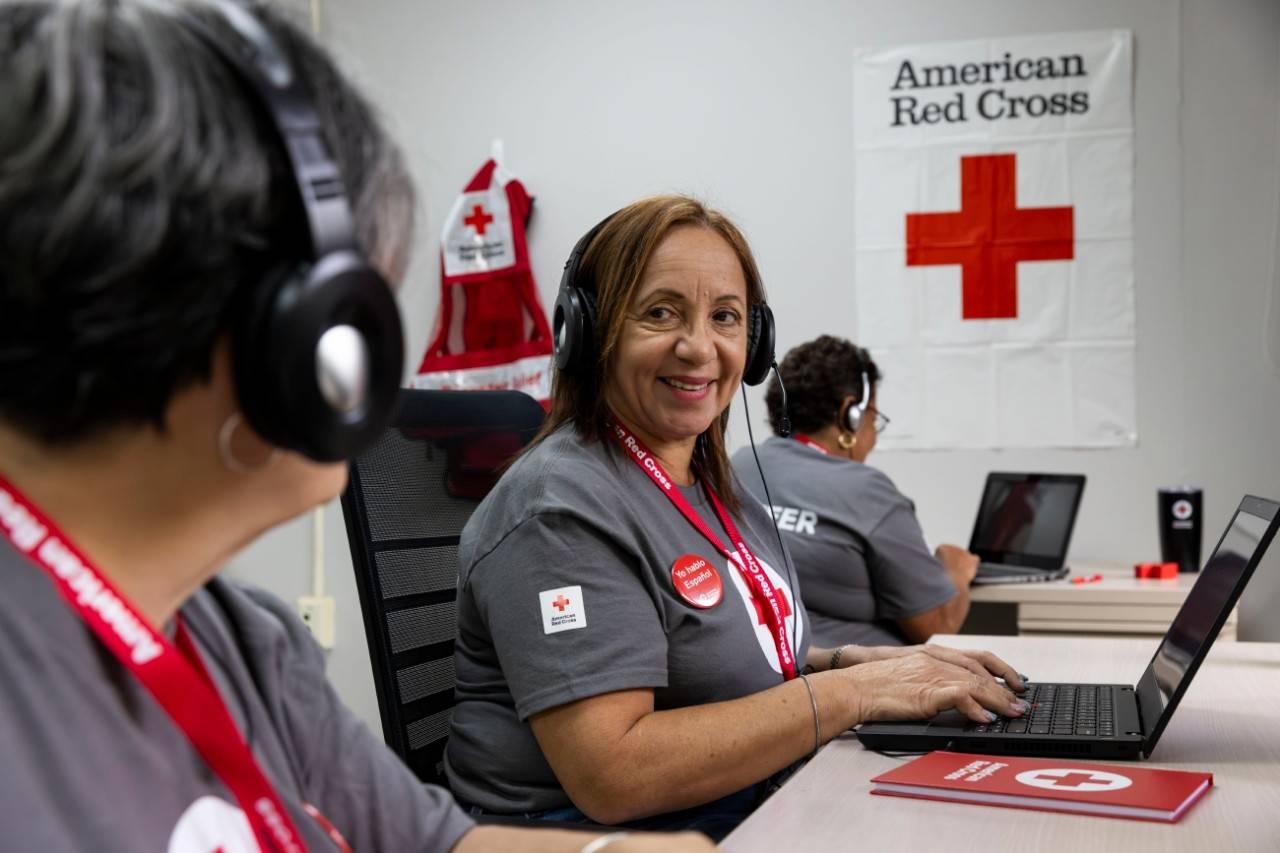 Foto posada de voluntaria en la oficina de la Cruz Roja atiende llamadas.