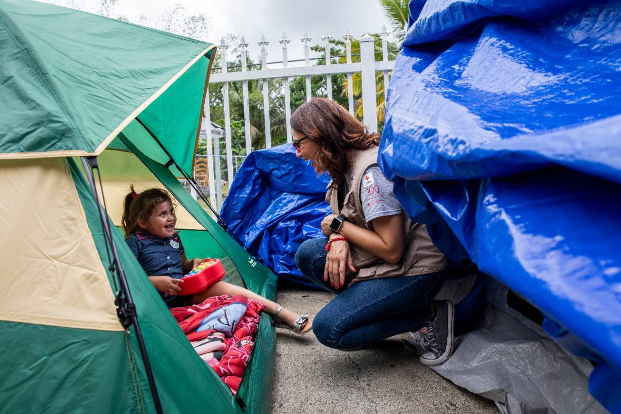 January 22, 2020. Guayanilla, Puerto Rico.
Camila, 8 years old, shares a melody in her toy piano with Red Cross member Grace, in what is now her new temporary bedroom at an outside tent in front of her house.
Photo by Scott Dalton/American Red Cross