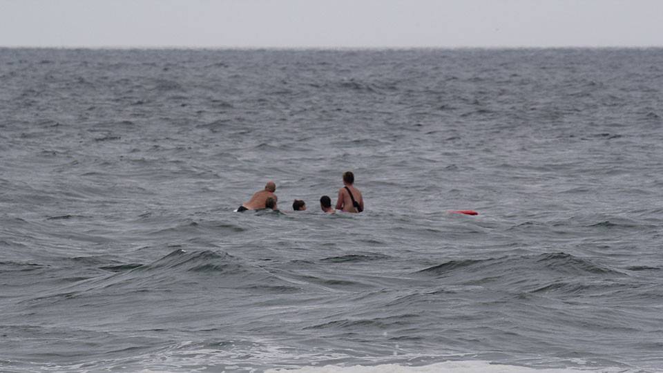 5 people swimming in the ocean's rough surf.
