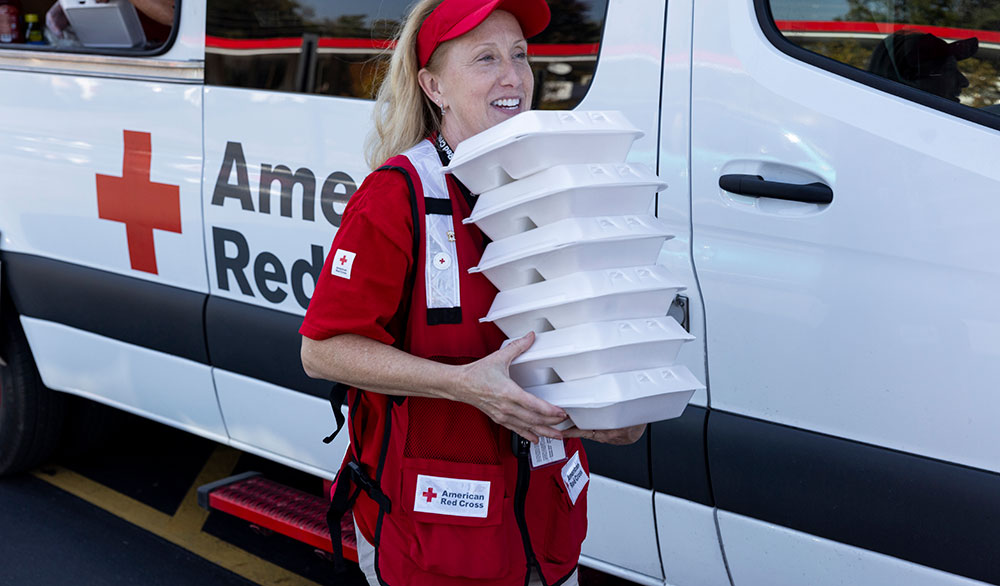 Red Cross volunteer carries to-go meals to hurricane survivors.