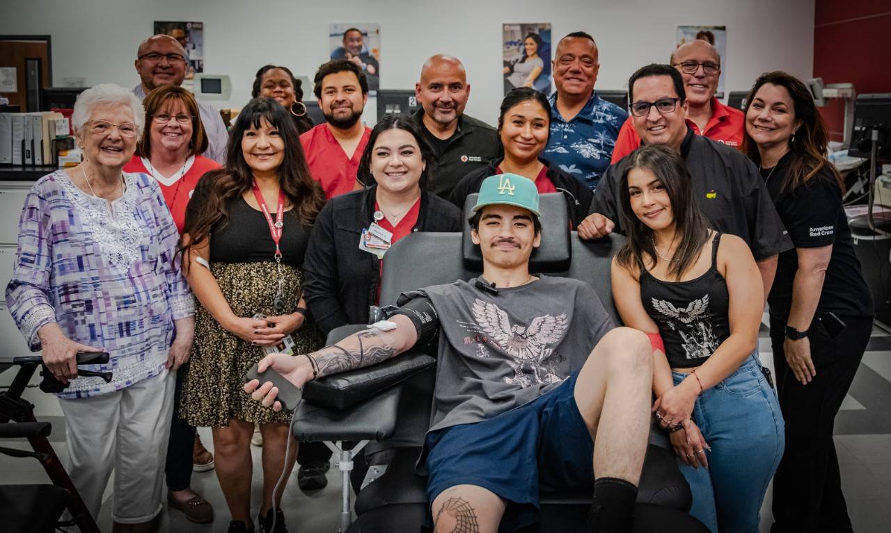 Group of people smiling and surrounding a blood donor.