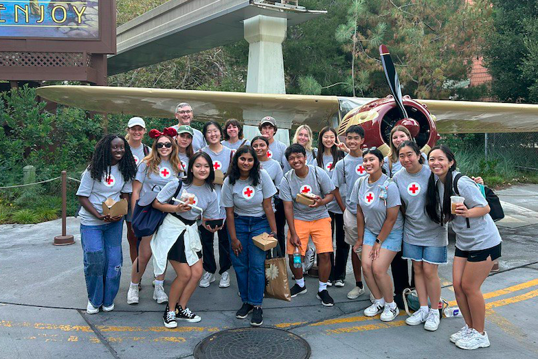 Red Cross Youth volunteers at the Disney Imagination Campus, standing in front of an airplane on display.