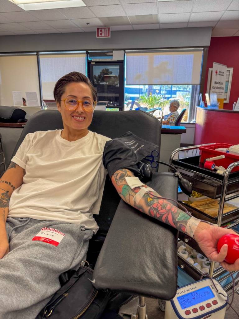 Individual donating blood and smiling.