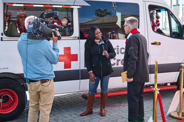 Fox news interviewing Red Cross volunteers in front of a Red Cross vehicle.