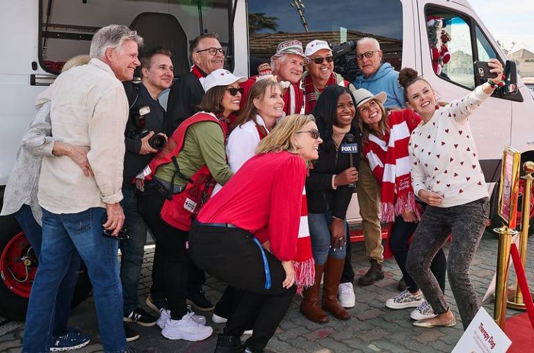 Red Cross volunteers and fox news taking a group photo in front of a Red Cross vehicle.