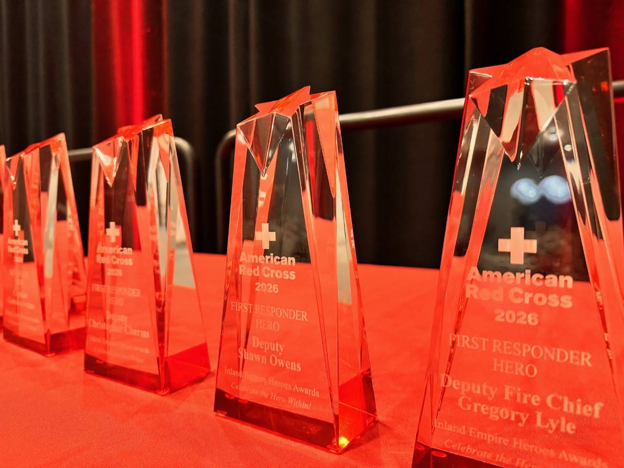 Close-up of glass American Red Cross Heroes Awards displayed on a table with a red table cloth