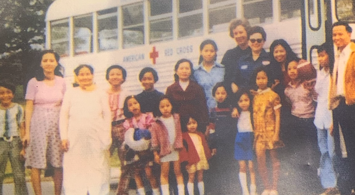 A family stands in front of a Red Cross bus in 1975
