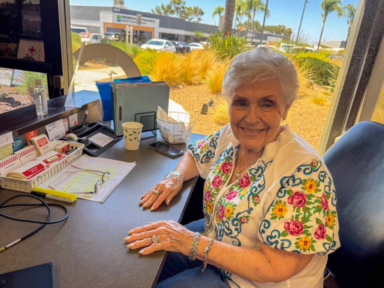 Woman smiles and sits at a desk at the Red Cross Blood Donation Center