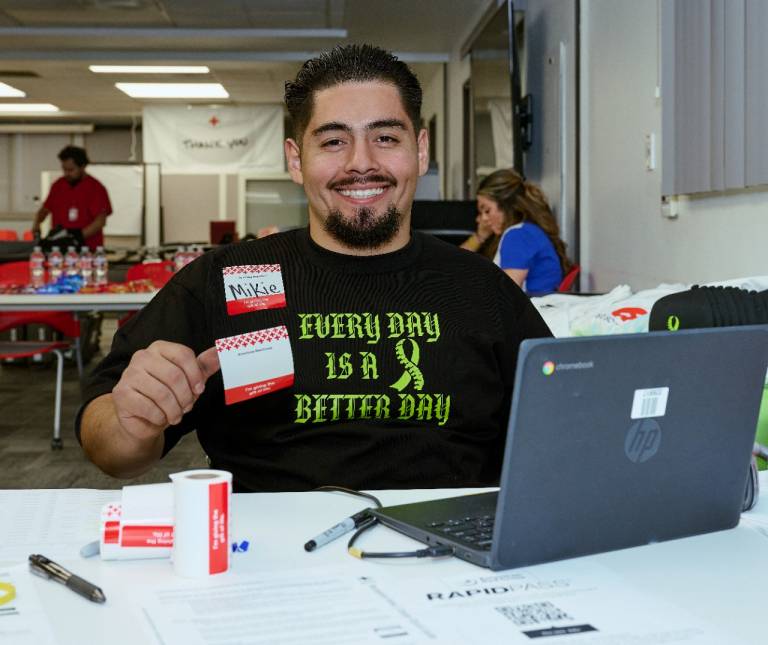 Smiling man in wheelchair at blood drive check in table