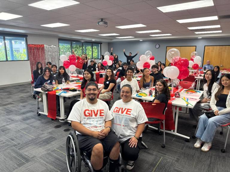 Smiling man in wheelchair in front of audience of teenagers
