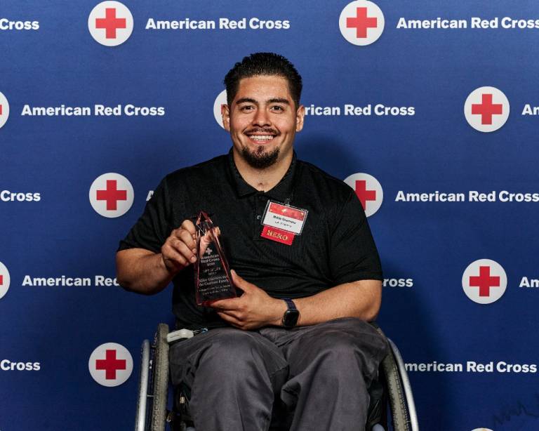 Smiling man in wheelchair holding award