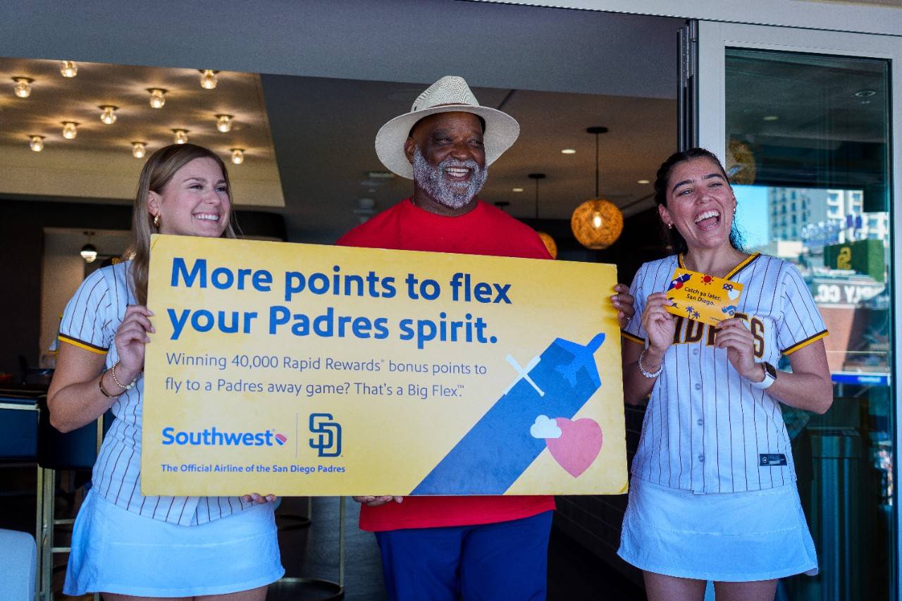 Phillip holding a Southwest Airlines poster and two Pad Squad members standing with him