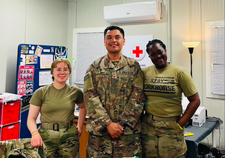 Three individuals pose together smiling in military uniforrms