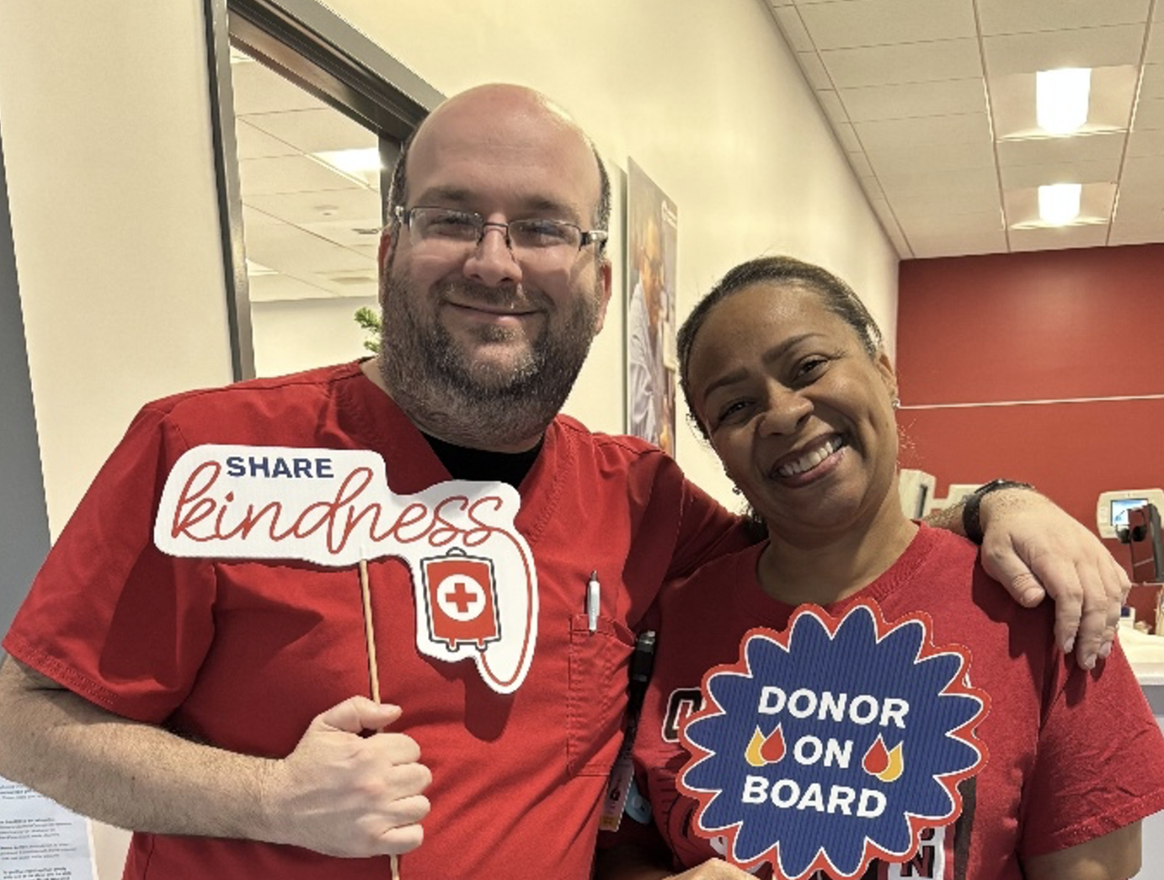 Man and woman pose together, smiling, in a Red Cross blood donation center