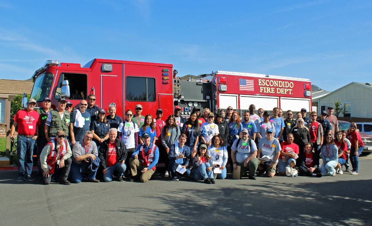 Large group of American Red Cross volunteers and community partners posing in front of a red Escondido Fire Department fire engine during a Sound the Alarm home fire preparedness event.