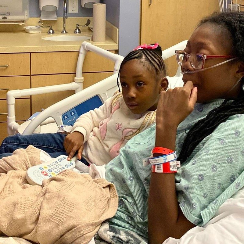 Mother in hospital bed with daughter laying next to her.