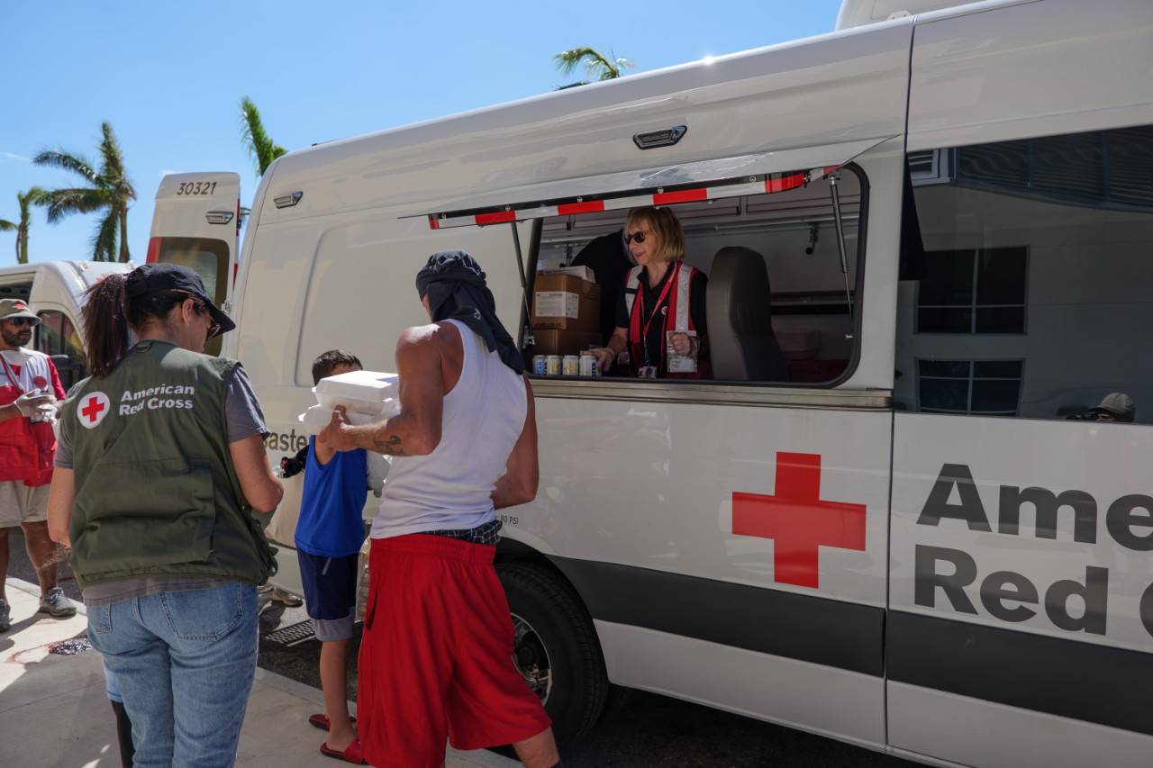 October 8, 2022. Harlem Heights, Florida. Red Cross volunteer Lynn Paul serves warm meals to a dad and his sons at the Harlem Heights Community Center. Photo by Brad Zerivitz/American Red Cross