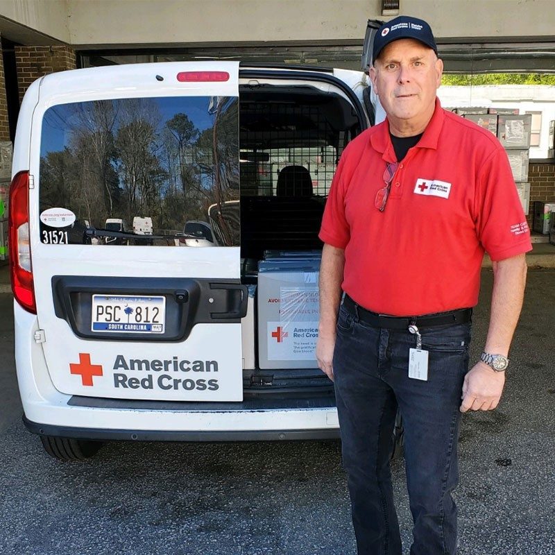 Roger Chaddick standing by back of Red Cross van