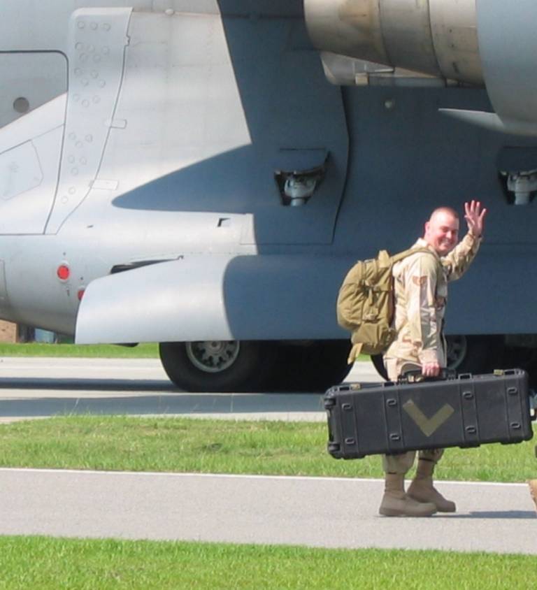 United state military member in uniform waves goodbye as he is about to board a military aircraft for an overseas deployment