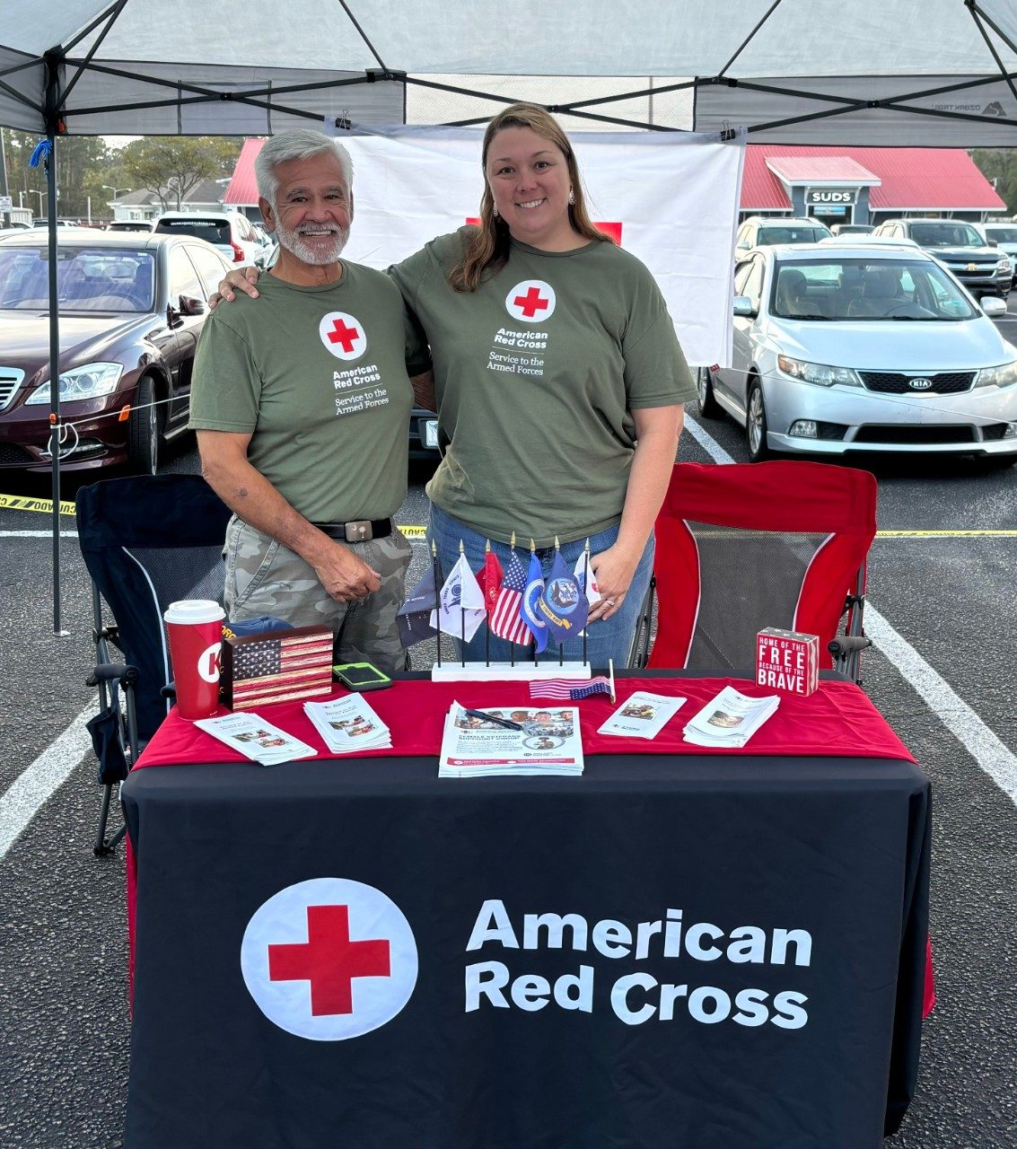 Robin Reynolds stands with another volunteer at a Red Cross table.