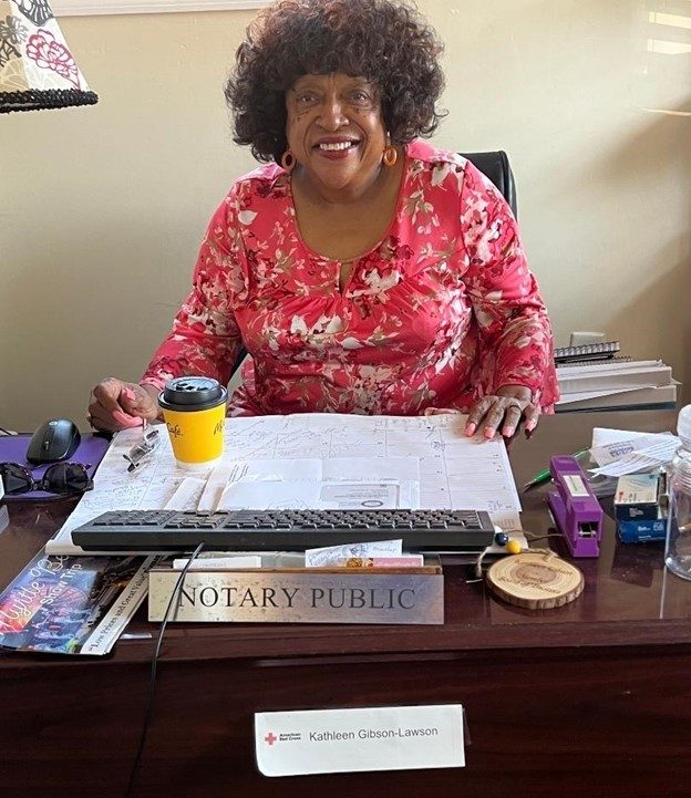 woman in red shirt smiling at desk