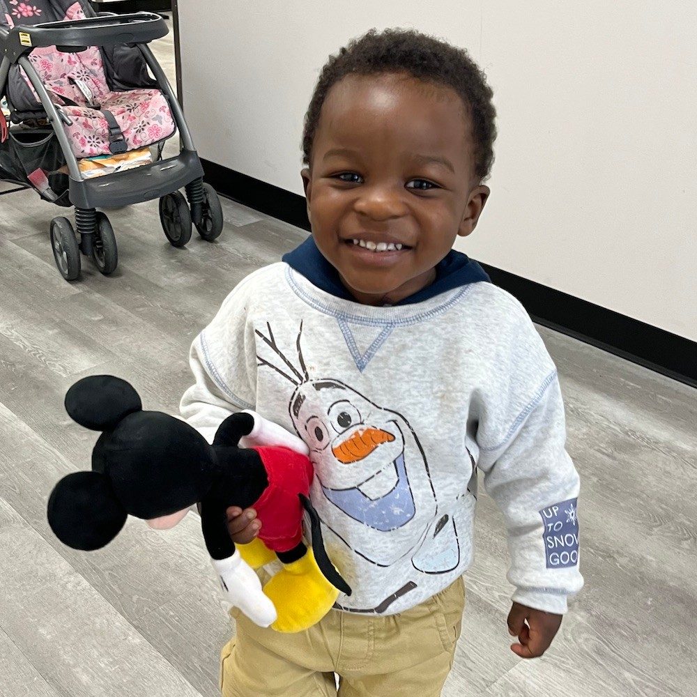 Toddler named Zayden holding a Mickey Mouse doll