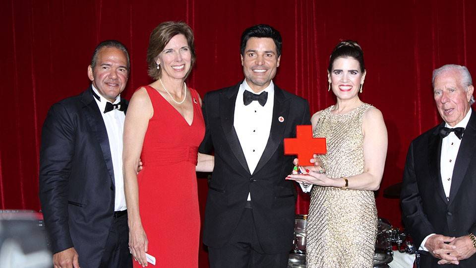five people in Black Tie attire with two of them holding a Red Cross award together.