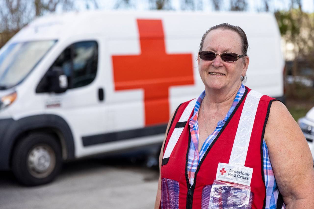 October 14, 2022. Ft. Myers, Florida.
Red Cross volunteer Claire Tryon has been volunteering with the Red Cross for 24 years and is celebrating her 100th disaster deployment. She is currently serving as a logistics lead at the Hurricane Ian disaster relief operation headquarters in Fort Myers, FL. “Tropical Storm Allison hit, and it was in my backyard where I live in Texas, so I called the Red Cross and told them, ‘I’m ready to go, what do I need to do?’” Tryon recalled. “It’s a wonderful organization – if you like to help people and you’re passionate, you have compassion, this is where you need to be. And we have something for everybody at the Red Cross.”
Photo by Scott Dalton/American Red Cross