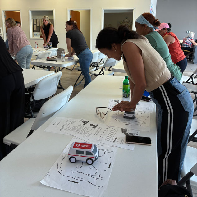 people in a classroom doing CPR training exercises on tables.