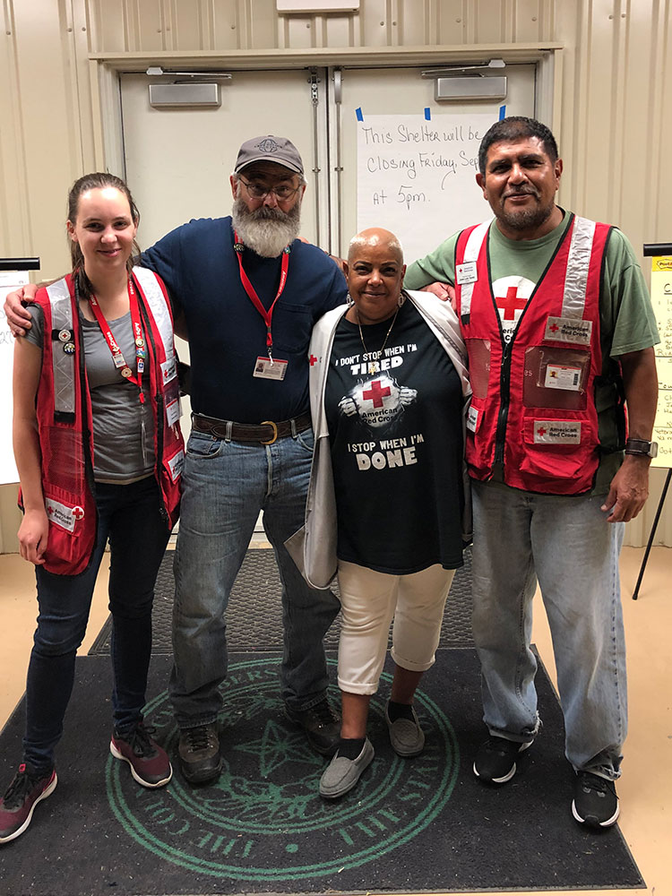 Red Cross volunteer, Cinnamon Reyes standing next to three other volunteers in a Red Cross shelter.