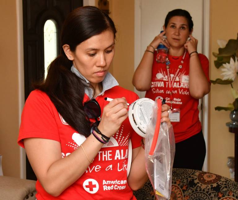 Eliza writes the date on the smoke alarm to be installed.