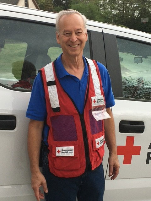 Gary Weinstein wearing a Red Cross vest and standing next to a Red Cross van.